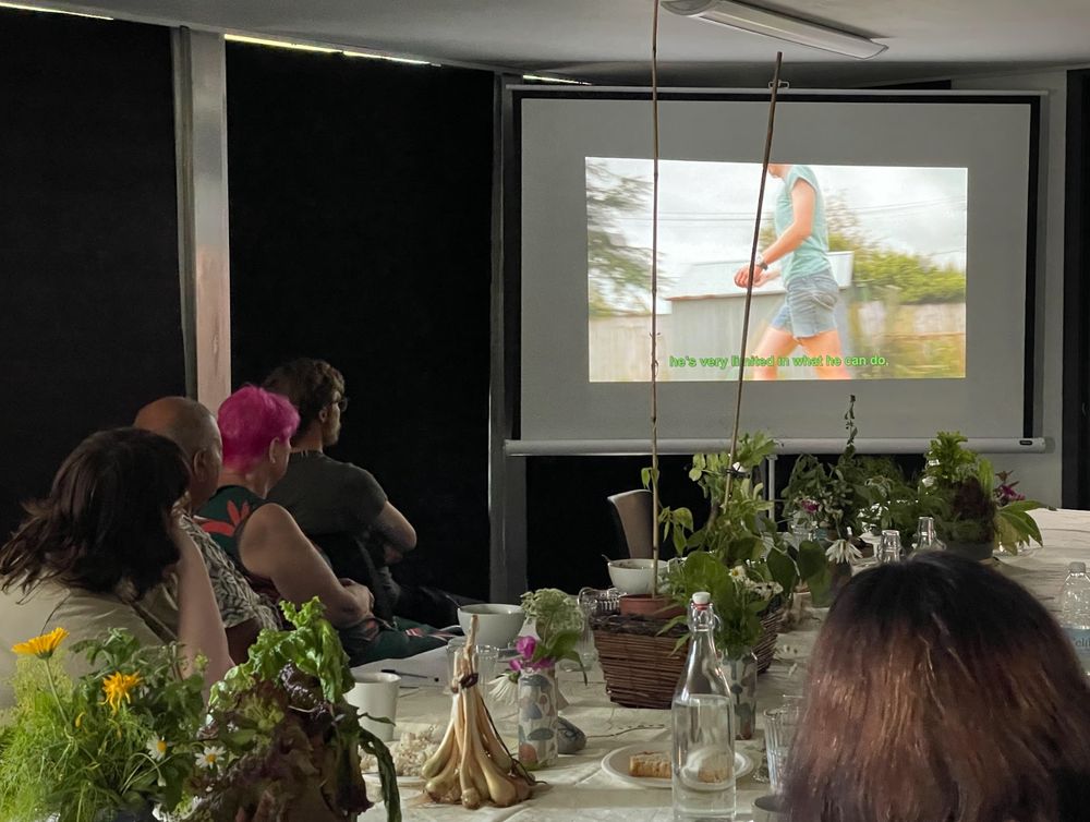 People sitting around a table and watching the short films on screen.