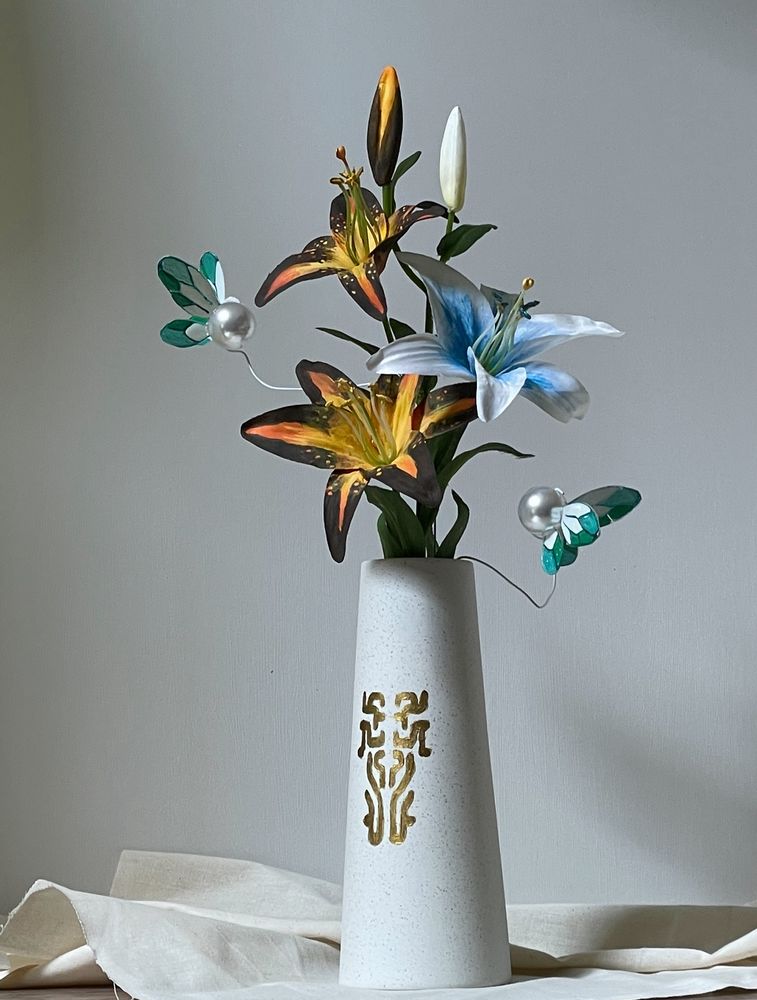 Zelda Sundelion flowers (yellow and black) with Zelda Silent Princess flowers (white and blue flowers) and Zelda fairies (white pearlescent with white and green wings) in a Zonai patterned vase and sitting in soft light 