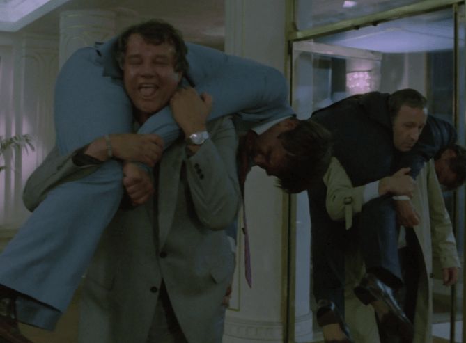 ChatGPT describes the image as "The image shows two men each carrying another unconscious or possibly deceased man slung over their shoulders in an indoor setting with ornate columns and reflective surfaces. The man in the forefront, carrying a man in a light blue suit, appears to be grimacing or struggling, indicating physical effort or emotional tension. The second man behind him, carrying another, is more solemn and focused. The scene suggests an intense moment, likely involving covert or desperate actions, possibly to move the individuals quietly or remove them from a dangerous situation within a formal or official building. The lighting and attire indicate a serious and professional atmosphere."

BotOfDarkness, version 2.0.23. AWS Lambda version: 1.14.