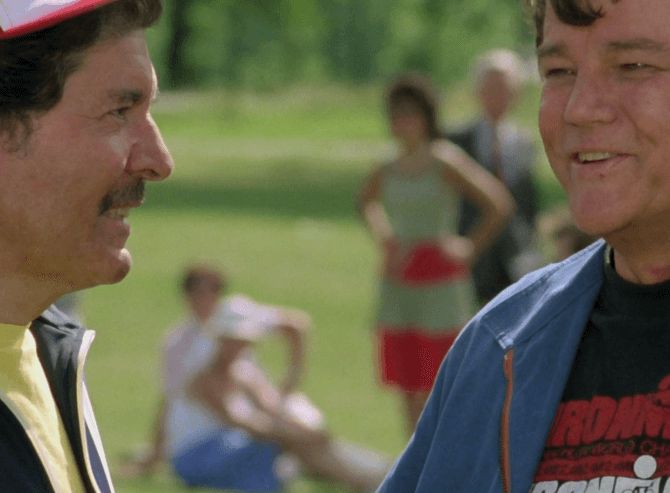 ChatGPT describes the image as "The image depicts two men engaged in a conversation outdoors, with a blurred background of people enjoying a park or garden setting. The man on the left has dark hair and a mustache and is smiling while facing the other man, who has short, light-colored hair and is also smiling. The man on the right appears to be wearing a blue jacket over a black T-shirt with red lettering. In the background, three individuals are visible: one woman standing with her hands on her hips, and two seated children, all casually dressed and seemingly relaxed. The scene conveys a moment of friendly interaction in a peaceful, recreational environment, possibly during a casual gathering or a day out."

BotOfDarkness, version 2.0.23. AWS Lambda version: 1.14.