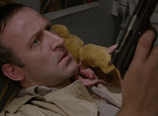 ChatGPT describes the image as "The image depicts a man lying on the ground, gazing intently at a device he is holding in his hand. He appears deep in thought, with a serious expression on his face. The setting looks like an outdoor or makeshift environment, possibly a rough or abandoned area, suggested by the visible wooden pallets or crates in the background. A yellow stuffed animal rests beside him, adding a contrasting element of innocence or comfort amid the tense atmosphere. His clothing is casual, and the scene seems to evoke a moment of introspection or concern, possibly amid a suspenseful or dramatic situation."

BotOfDarkness, version 2.0.23. AWS Lambda version: 1.14.