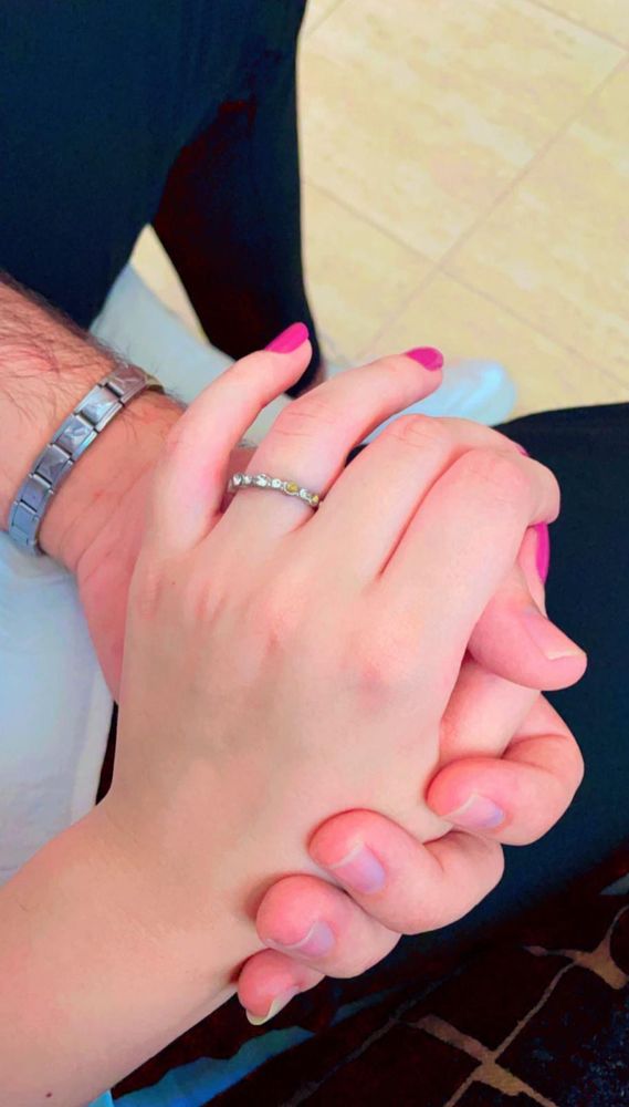 Photo of two hands holding, Dima is wearing a small engagement band 