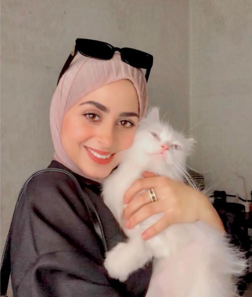 Aseel smiling with a fluffy cat and looking healthy 