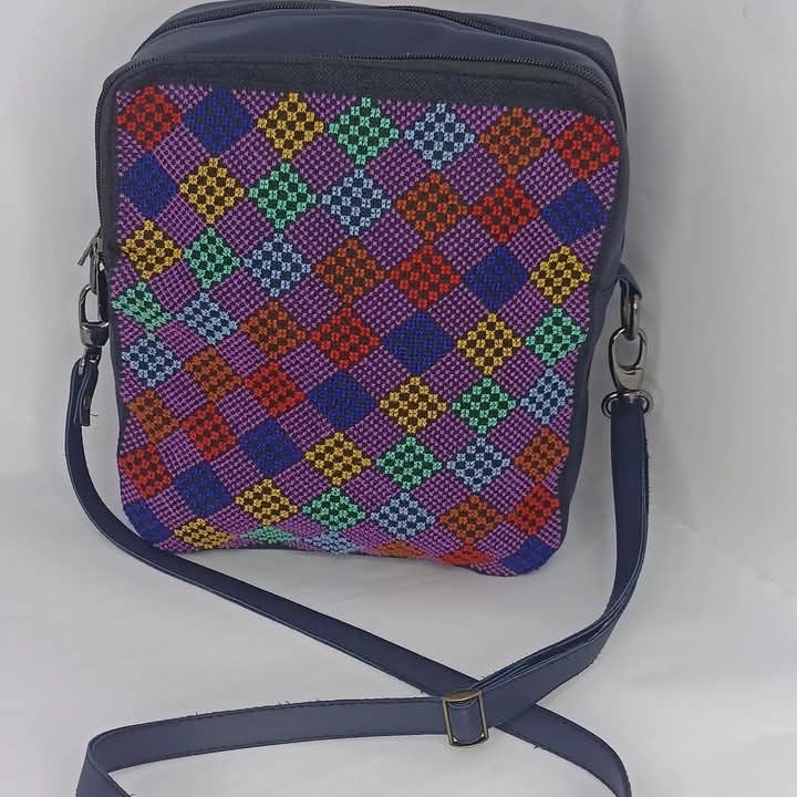 Photo of a navy bag with a bunch of grid, geometric embroidery, in rainbow colors on it
