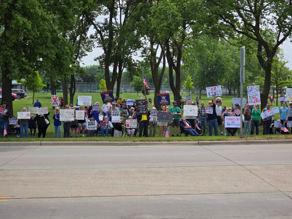 A wide shot of citizens with signs lining the street.