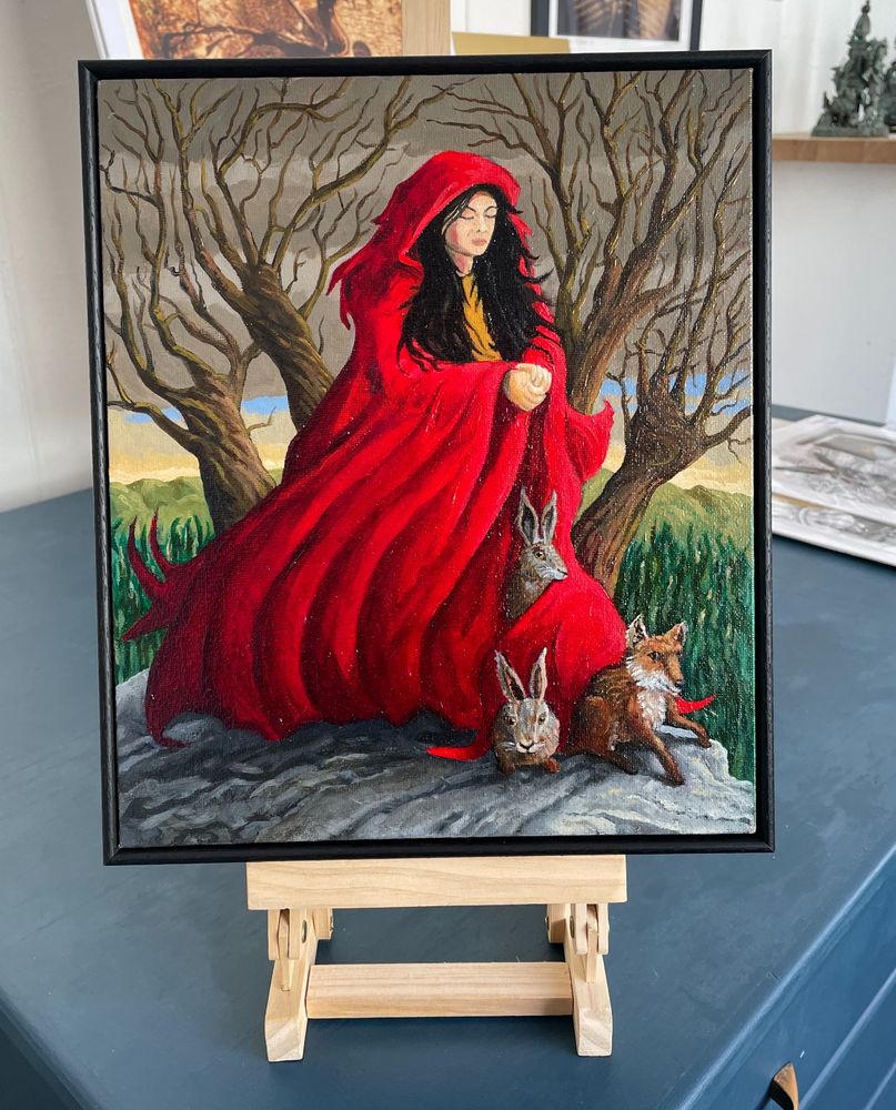 A painting called Melangell's Cloak, depicting Melangell in her red cloak, forest creatures are coming out of it after she sheltered them from a hunting party. 