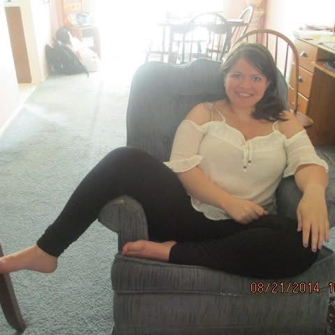 me sitting in a blue recliner in my parent’s house in 2014. i’m wearing - white cold-shoulder top and black leggings. my hair is in a side pony