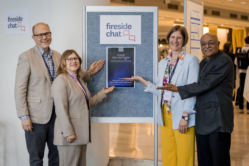 Picture of Jukka Pirttilä, Maria Jouste, Pia Rattenhuber and Ravi Kanbur in front of a poster of 'Poor protection' book, at the 2025 WIDER Development Conference.
