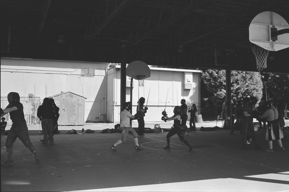 A black and white photo of a medieval weapon sparring event 