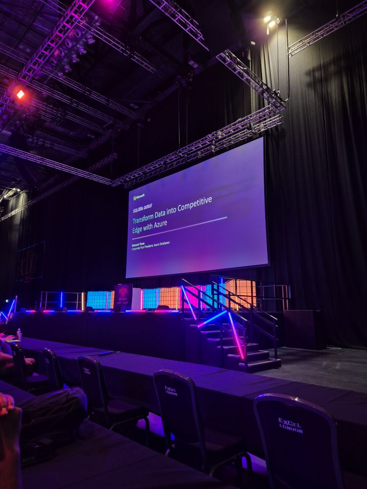 A presentation slide on a screen on a stage all illuminated in neon