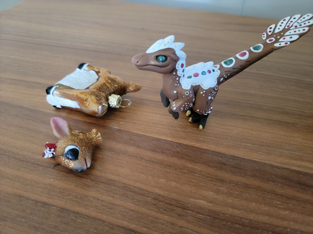 A Christmas ornament of Clarice the Reindeer appears to have been attacked by a gingerbread velociraptor