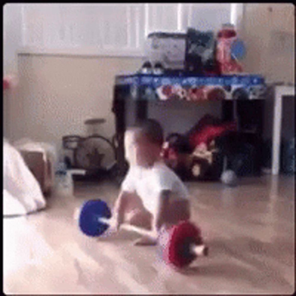 a baby is sitting on the floor holding a barbell .