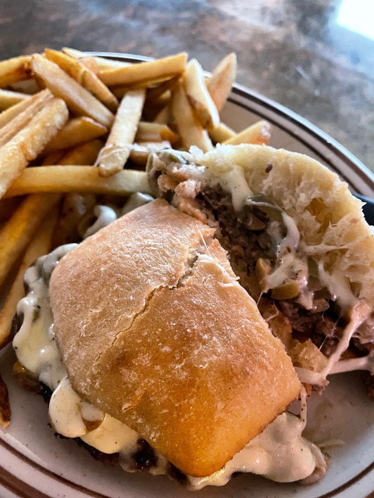 Gourmet bar burger-topped with grilled olives and mozzarella on a ciabatta bun with real potato fries.