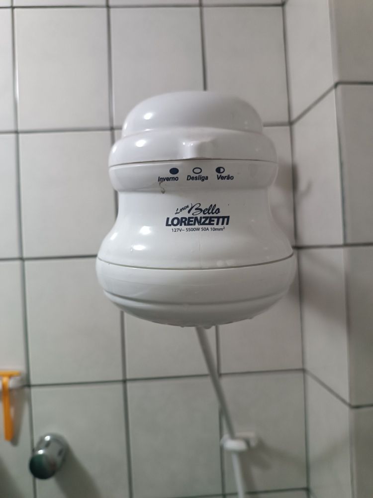 Foto de um chuveiro Lorenzetti branco. A posição da tecla deslizante que indica a temperatura da água se encontra na posição "Desliga"