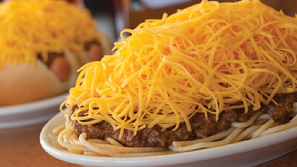 a plate of skyline chili served over pasta with several pounds of shredded cheese on top o