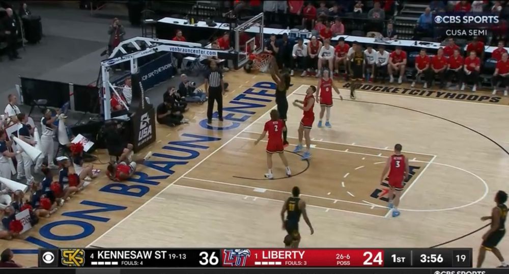 A Kennesaw State player dunks to give the Owls a 14 point lead on Liberty, whose players have decided to stand nearby and watch the Owls score in tribute to Jerry Falwell Jr