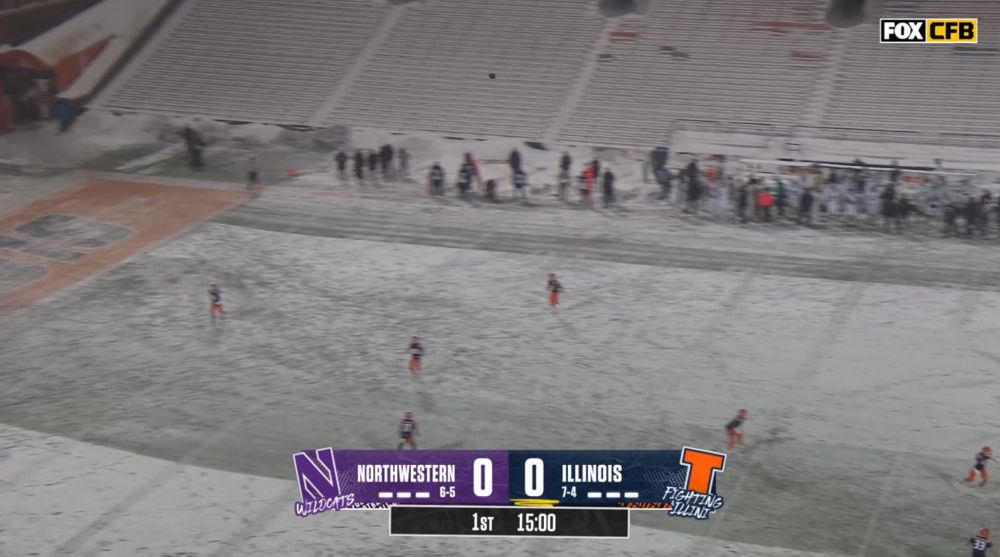 a kickoff on a snowy field in front of snowy stands