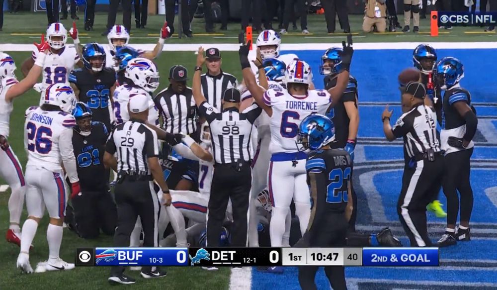 The Bills playing the Detroit Lions, who are wearing black jerseys with metallic blue helmets, metallic blue uniform numbers with white bordering, and white lettering on the back of their jerseys