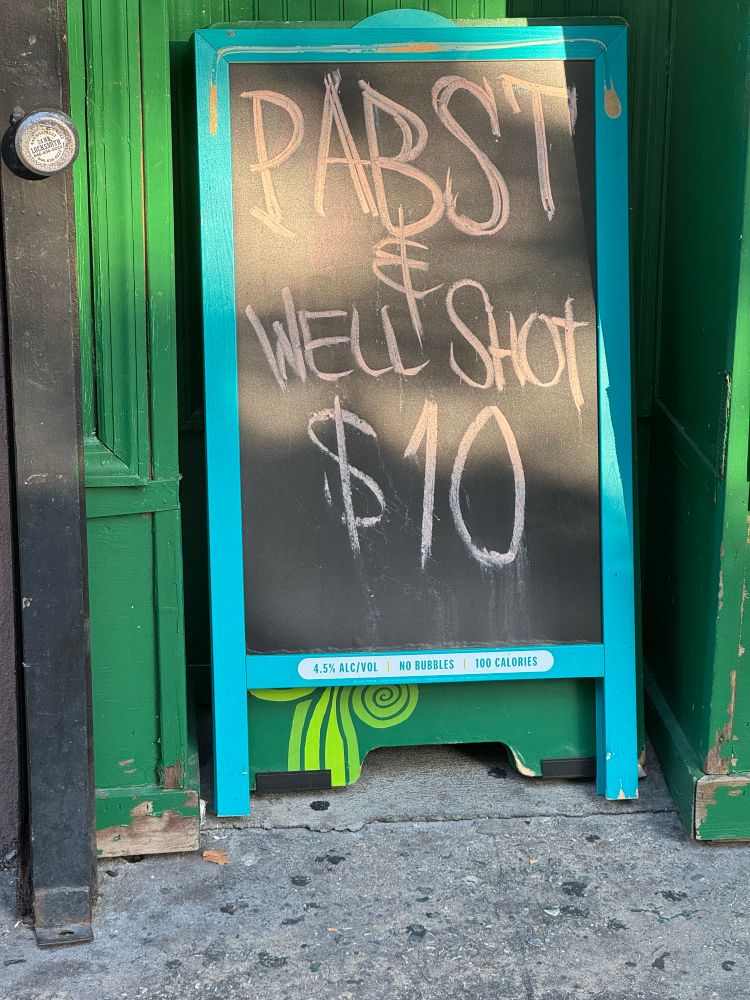 A sign outside a bar that says “Pabst + well shot $10”