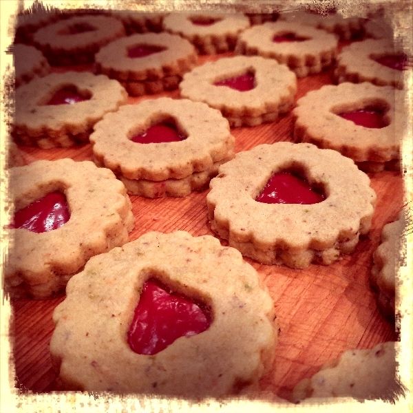 Linzer Kekse mit Herzlücke oben und Marmeladenfüllung auf einen Holzbrett