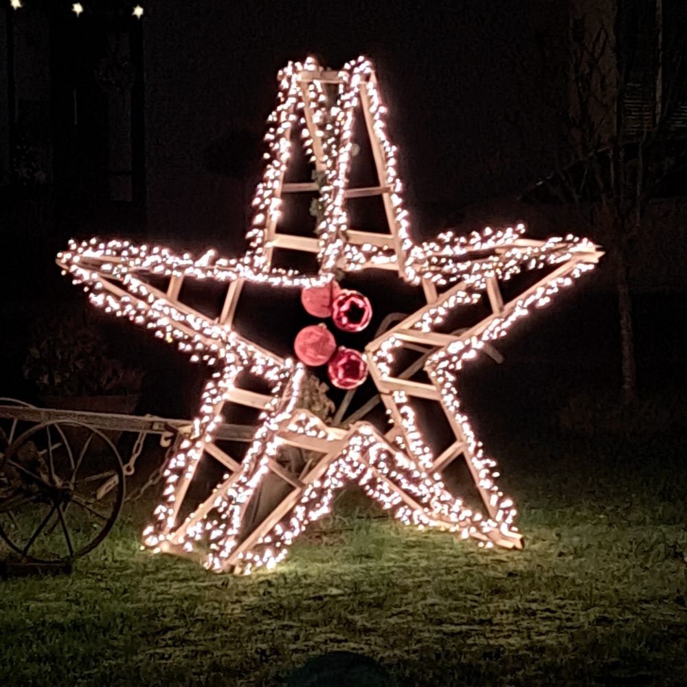 Doppelter großer Stern aus Lichterketten. In der Mitte der Sterne hängen 4 rote Weihnachtskugeln
