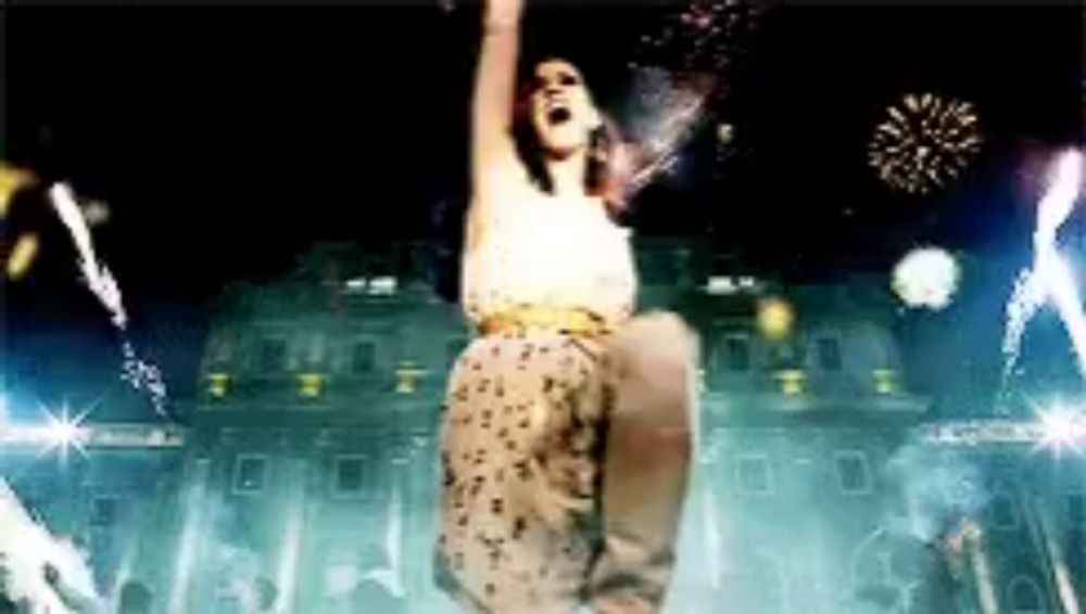 a woman is dancing in front of a building with fireworks in the background