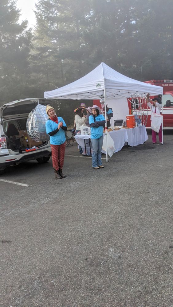 Volunteers celebrating bicyclists as they come in for a break. A tent with refreshments.