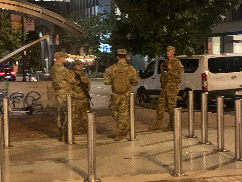 Group of National Guard standing by the south entrance to the Dupont Circle metro. One of the guard carries an M4 carbine assault rifle. 