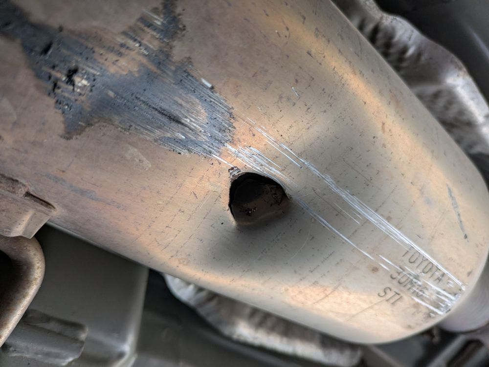 A car's resonator with a big round hole punched in it 