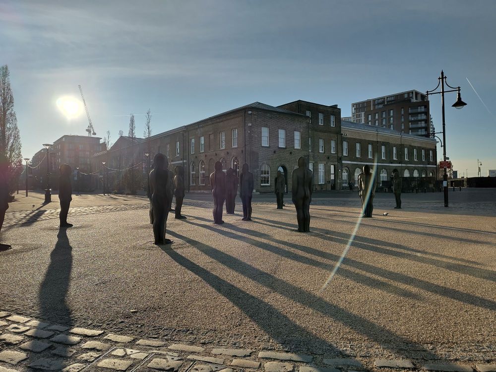 Outside venue Woolwich Works, multiple cast iron human mould sculptures stand in the winter sun, casting long shadows on the pavement.