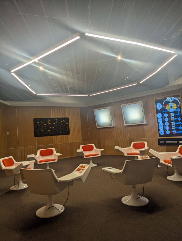 3D render of Project Cybersyn operation room in Barcelona Design Museum. 7 white chairs with red cushions, in a circle, within a control room.  Dashboard on the wall convey economic / factory data. 

How to Design a Revolution: The Chilean Road to Design 

is a comprehensive exhibition on graphic and industrial design during Salvador Allende’s government in Chile (1970-1973). An exceptional case in the history of design, where the unprecedented act of choosing a revolution through the ballot box led to the first instance of a country to collectively designing through socialism and democracy..  