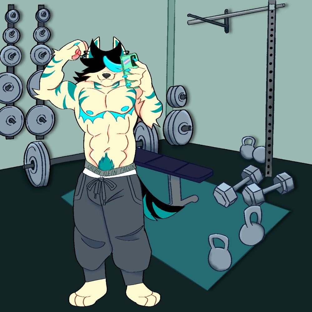 Chai standing in a gym in front of a mirror, taking a selfie with one hand and flexing his bicep while surrounded by workout equipment