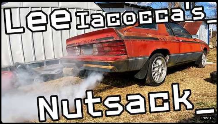 Youtube thumbnail of a decrepit 1982 Dodge Charger blowing smoke with the text "Lee Iacocca's Nutsack_" superimposed over it. For the record, the video is about restoring the pictured car to working condition.