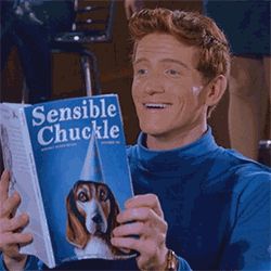 a man in a blue sweater is reading a book called sensible chuckle