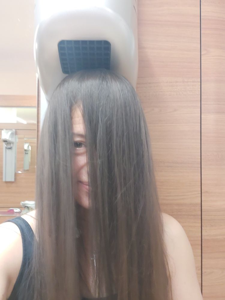 Ein Selfie von mir unter einem Fön in einer Schwimmhalle. Meine Haare bedecken mein Gesicht komplett, bis auf einen kleinen Spalt. Da illere ich durch. Man kann einen kleinen Gesichtsauschnitt sehen.