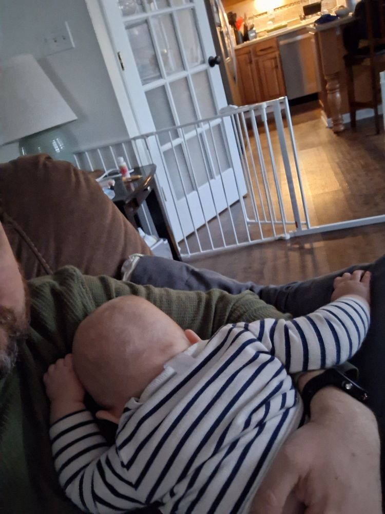 Baby asleep face-down on dad's chest
