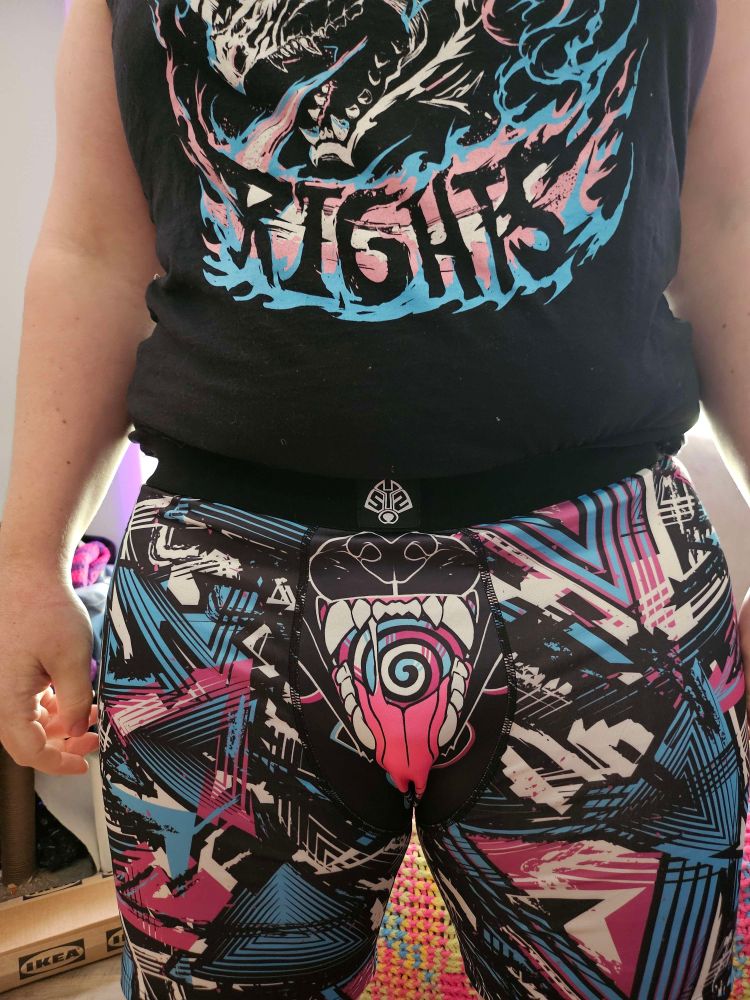 close up of very bright underwear, in trans colours. There is an animal mouth by the crotch, open and tongue hanging out. 