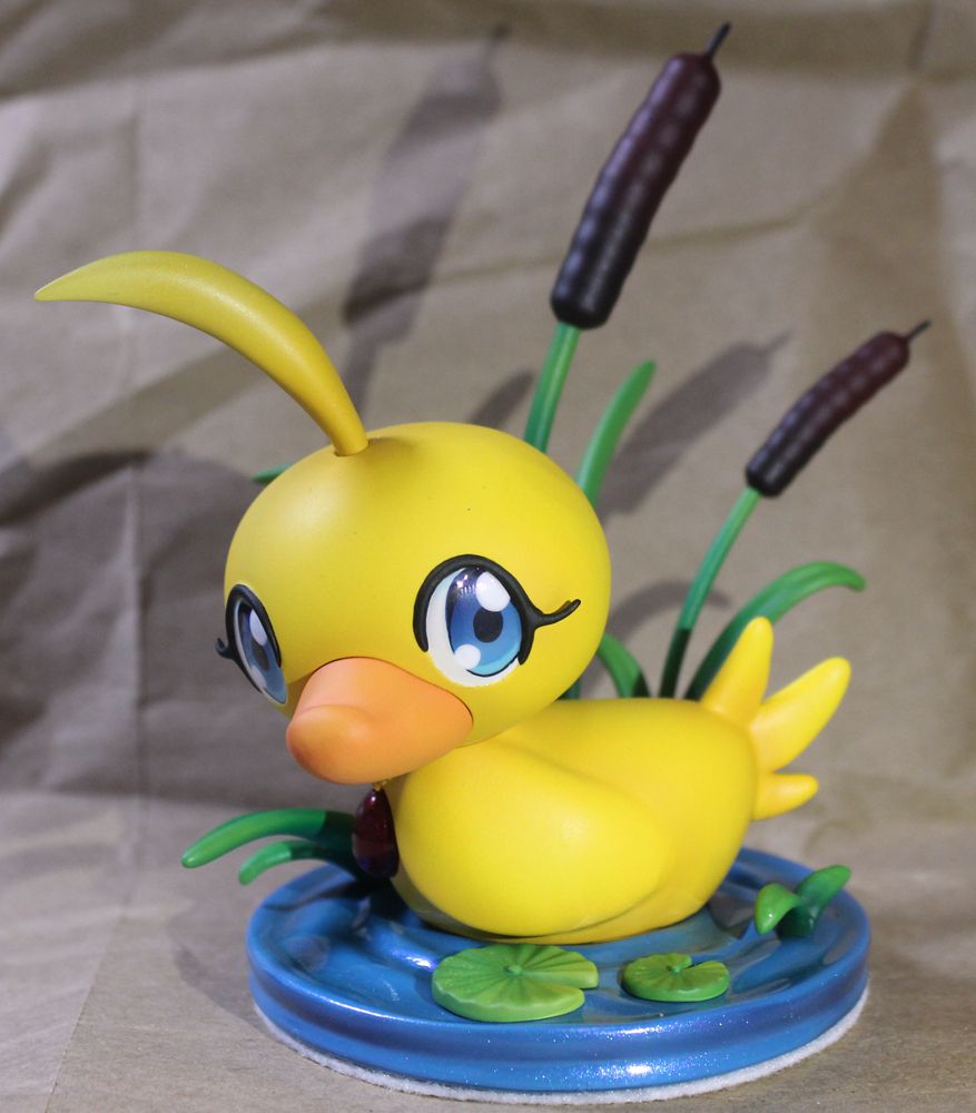 Ahiru/duck as a duck sitting on the water looking to the side, two cattails are behind her and she is wearing her pendant