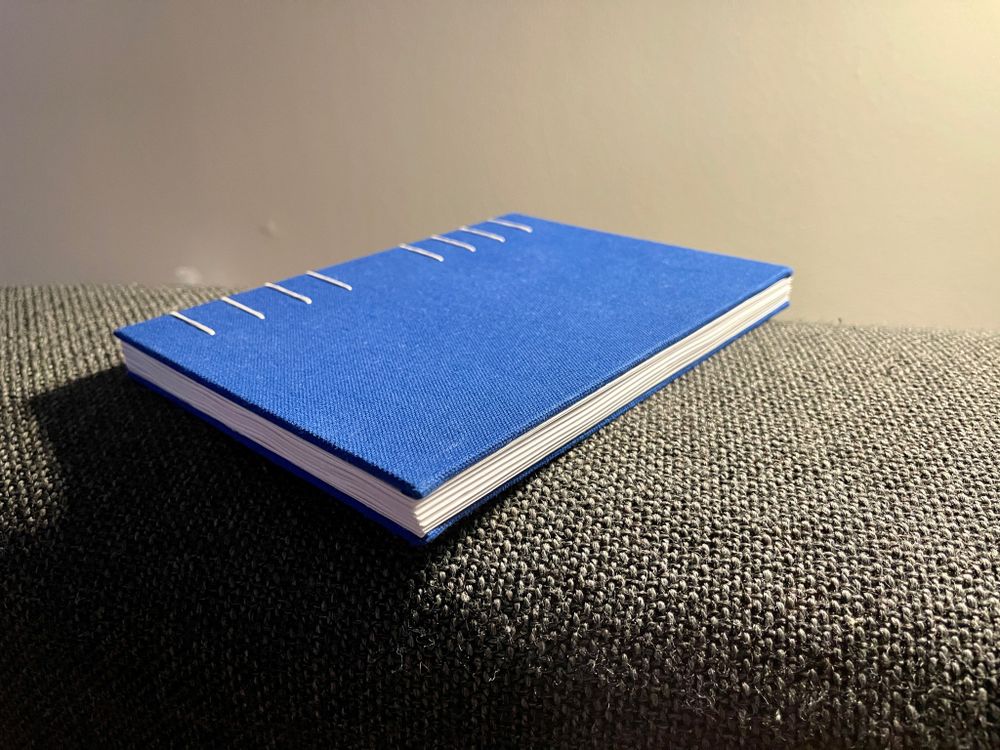 horizontal view of hand sewn notebook, showing imperfect signatures but an overall pleasing result of doing craft