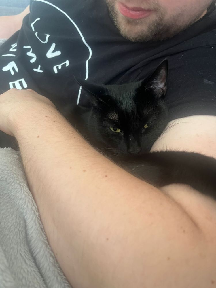 A guy cuddling a black cat