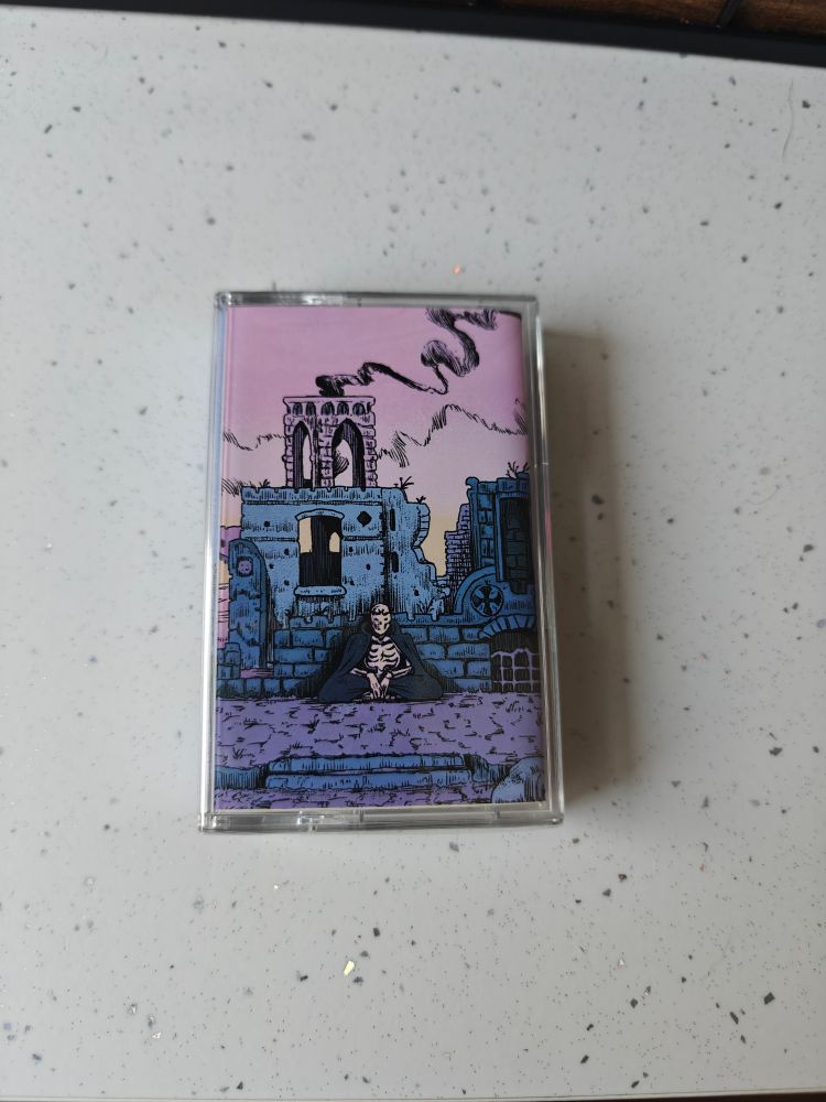 Cool lil cassette depicting a skeleton sitting in a ruin. The sky is pink