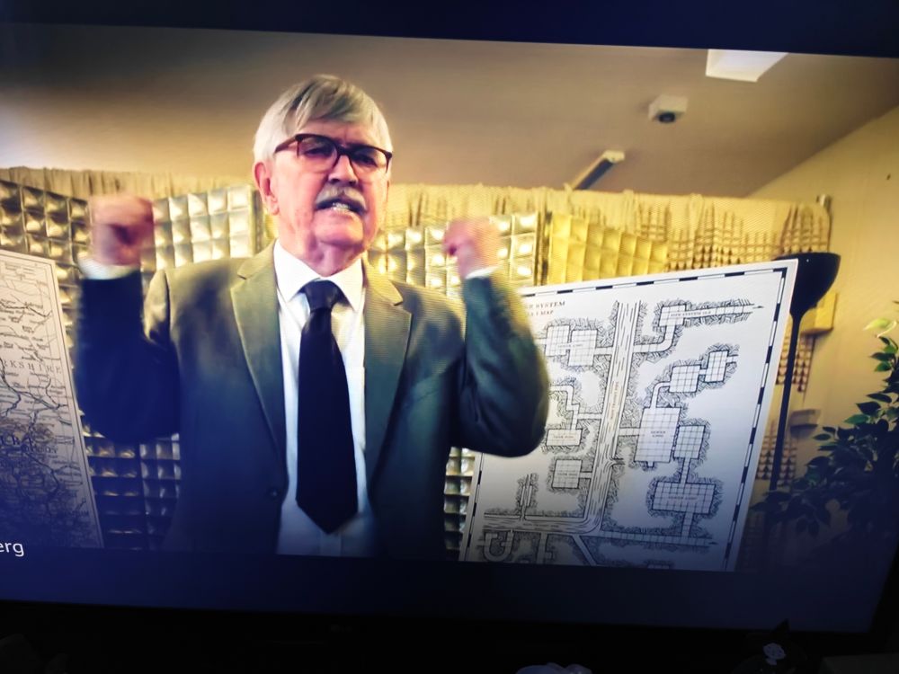 Man giving impassioned speech in front of a poster of a sewer dungeon