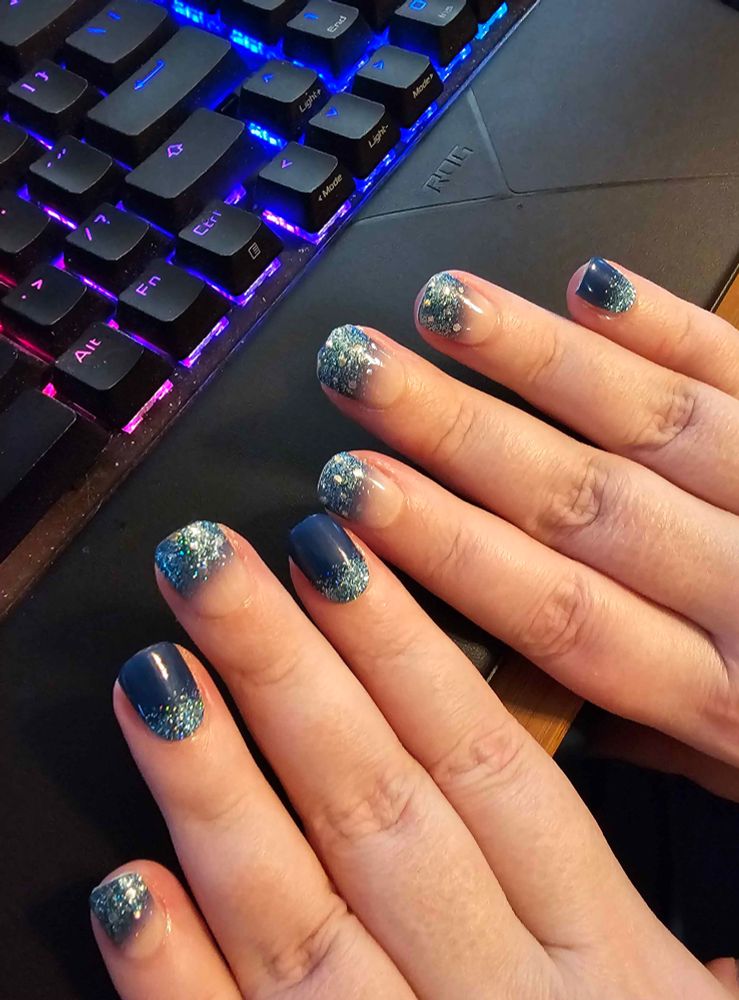 Picture of two pale-skinned hands with a vivid blue and glittering blue manicure 