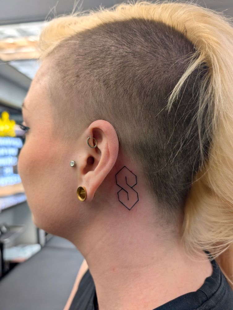 A photo of me mostly turned to the side, showing a Cool S tattooed behind my ear.