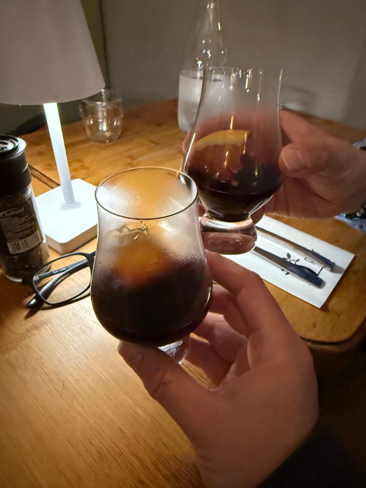 Zwei kleinere Gläser, gefüllt mit einer dunklen Flüssigkeit und einer Orangenscheibe. Die Gläser sind zum Teil beschlagen wegen des heißen Glühweins.