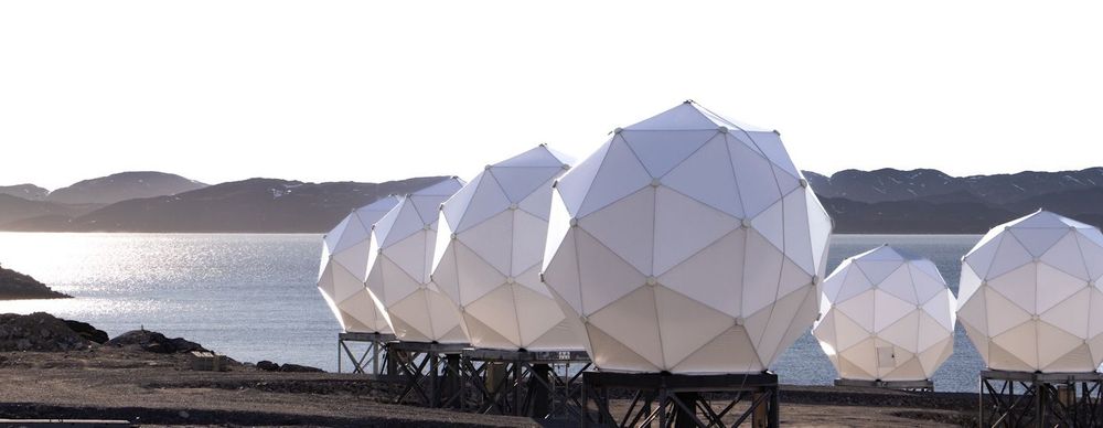 Radar and satellite domes in Greenland with mountains and ocean in the background.