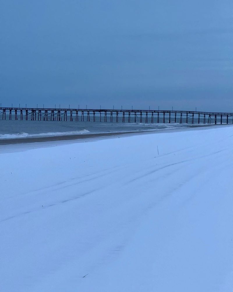 Snow on a beach with a pier