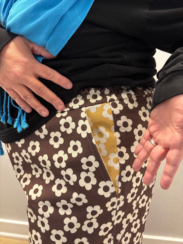 Close up of the pants pocket, showing a yellow and white flower pattern identical to the brown and white flower pattern.