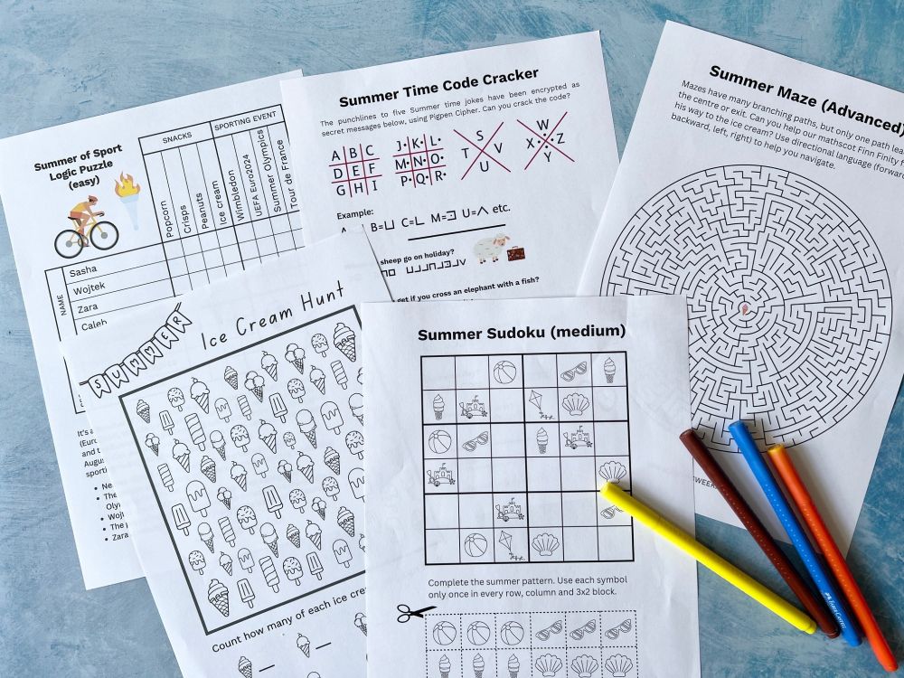 A photograph showing print outs of five different kinds of puzzles, including a logic puzzle, pigpen cipher, maze, counting puzzle and picture sudoku. Some colouring pens are also in the photo.