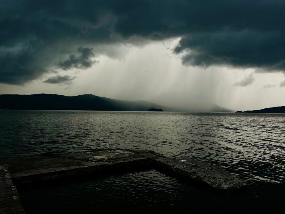 A photo of dark storm clouds dumping rain on Owl’s Head across the dark silvery water of Lake Memphremagog. 

Photo taken by my 16 year old.